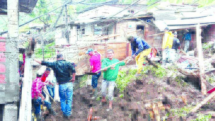 Residentes trabajan para desenterrar una casa destruida durante un deslizamiento de tierra en Manizales.