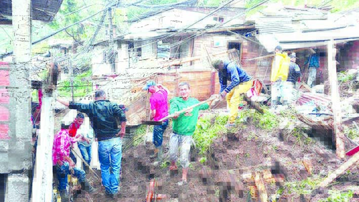 Residentes trabajan para desenterrar una casa destruida durante un deslizamiento de tierra en Manizales.