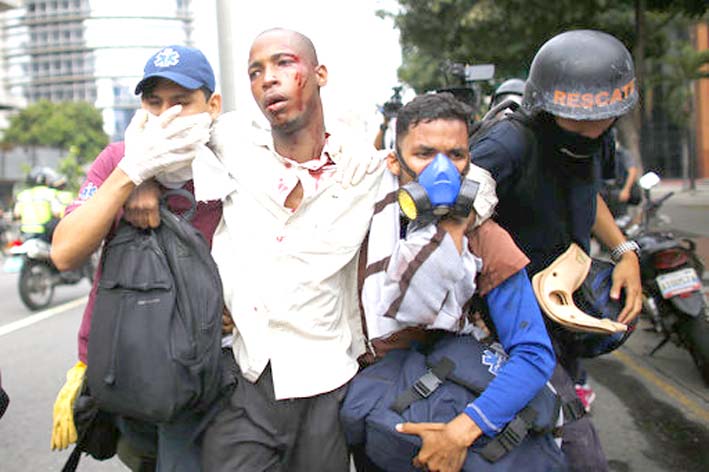 Los paramédicos asisten a un hombre herido durante los enfrentamientos con las fuerzas de seguridad durante las protestas pidiendo la renuncia del presidente.