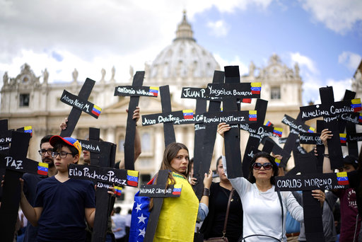  Los manifestantes sostienen cruces negras adornadas con banderas de Venezuela y con los nombres de los que murieron en semanas de violentas manifestaciones  