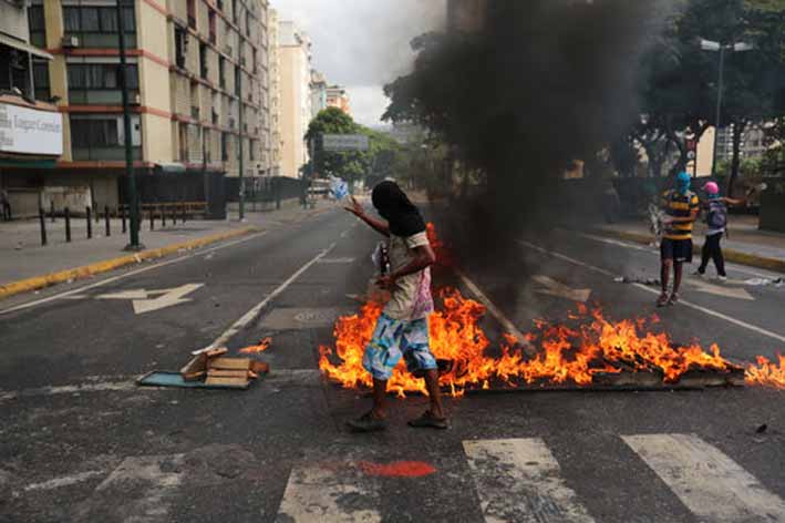 Manifestantes contra el gobierno supervisan una barricada ardiendo en Maracay. Los manifestantes han inundado las calles saqueando decenas de negocios.