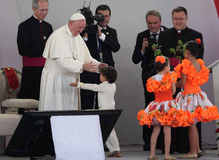 El papa Francisco recibe a un niño con los brazos abiertos en un acto para promover la reconciliación con un grupo de víctimas del conflicto armado de más de medio siglo en Colombia.