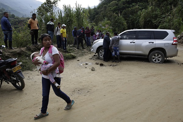 Una mujer camina este miércoles junto al carro en el que se transportaban cinco indígenas que fueron asesinados presuntamente por parte de disidencias de las FARC, en Tacueyó, Cauca, Colombia.