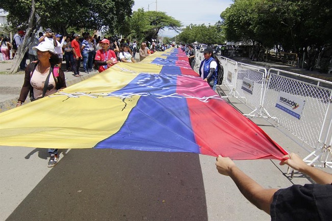 Un grupo de personas sostiene una bandera en el puente Simón Bolívar durante un acto de reapertura de la frontera entre Colombia y Venezuela en Cúcuta.