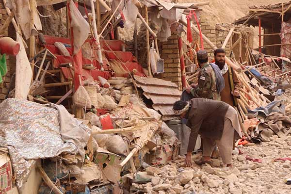 Residentes locales caminan entre los escombros de un edificio parcialmente derrumbado tras un terremoto en Samangan. EFE/EPA/Hamid Sabawoon