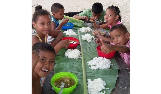 Niños guajiros que reciben los alimentos en hojas de bijao.