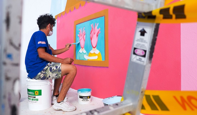 La fotografía muestra a un artista urbano mientras pinta un mural para el sexto Festival de Arte Urbano Killart, en Barranquilla.